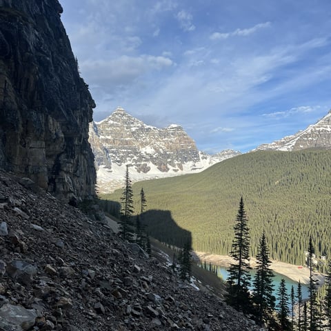 Rocky mountain peaks with forested valley, evergreen trees, and a blue lake nestled in alpine wilderness